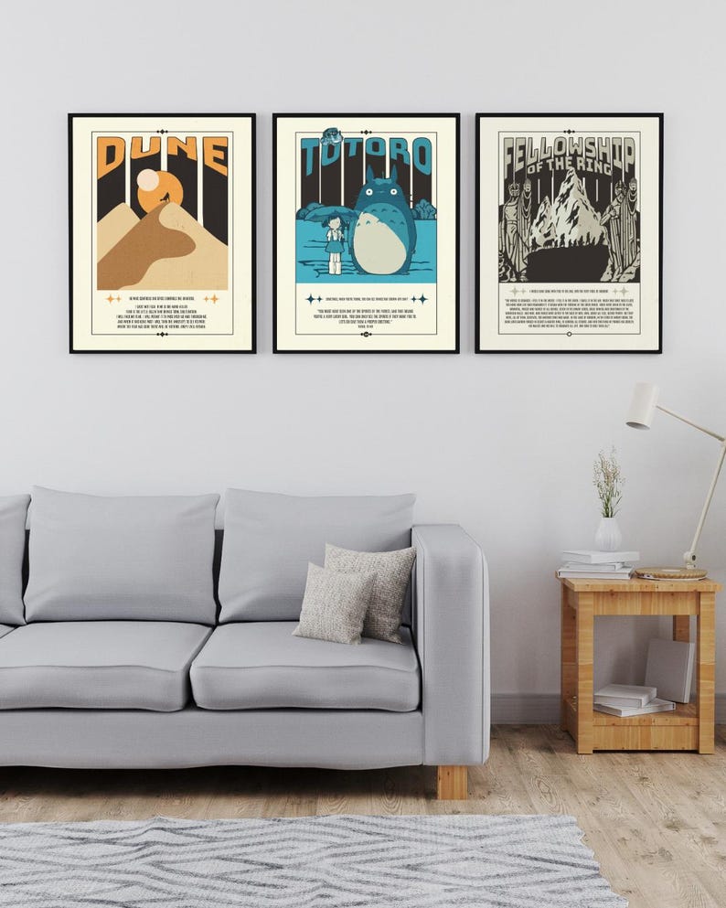 Może przedstawiać: Trzy oprawione plakaty filmowe wiszą na białej ścianie nad szarą sofą. Plakaty przedstawiają projekty w stylu vintage dla "Dune", "Totoro" i "Fellowship of the Ring". Każdy plakat ma czarną ramę i zawiera tekst i ilustracje.