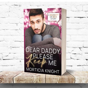 Puede incluir: Portada de libro con fondo rosa y copos de nieve. La portada presenta a un hombre con barba y una expresión seria. El título del libro es "Querido Papá, Por Favor, Quédate Conmigo" de Morticia Knight. El libro está etiquetado como una "Historia Traviesa o Amable".