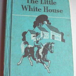 May include: Vintage book titled "The Little White House" with a teal cover. The cover features a black and white illustration of a person riding a horse in front of a house. The book's title is in large white letters.