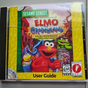 May include: A Sesame Street The Adventures of Elmo in Grouchland CD-ROM jewel case featuring Elmo, Oscar the Grouch, and other characters. The cover includes the title, the text Help Elmo find his blanket in an activity packed adventure, and a Mattel Media logo.
