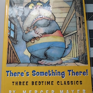 May include: A children's book titled "There's Something There!" with a yellow cover. The cover features a cartoon illustration of a large, blue cat-like creature holding a teddy bear. The text "THREE BEDTIME CLASSICS" and the author's name are also visible.