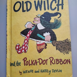 May include: A hardcover children's book titled Old Witch and the Polka-Dot Ribbon by Wende and Harry Devlin. The yellow cover features a black-clad witch with green hair flying on a broomstick while holding a long red ribbon with white polka dots.