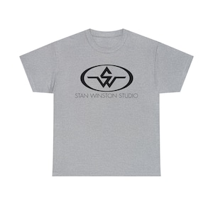 May include: A gray t-shirt with a black logo featuring the letters "SW" inside an oval with a line above and below. The text "STAN WINSTON STUDIO" is printed below the logo.