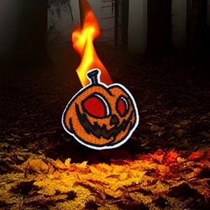 May include: A fiery orange and brown pumpkin with a spooky face is set against a dark, foggy forest background. The pumpkin is on fire, with flames rising from the top.