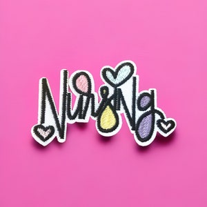 Può includere: Una toppa ricamata nera con la parola "Nursing" in un carattere stilizzato. La toppa ha cuori e altre forme colorate intorno alle lettere.