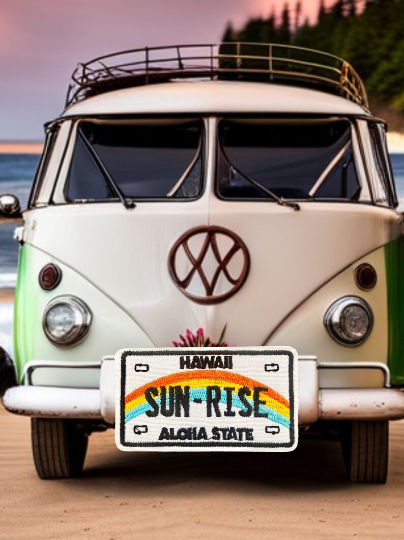 May include: A white vintage Volkswagen van with a rainbow license plate that reads "HAWAII SUN-RISE ALOHA STATE".