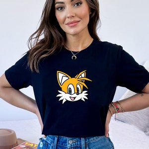 May include: A black t-shirt with a cartoon image of Tails from the Sonic the Hedgehog video game series. The image is yellow, orange, and blue.