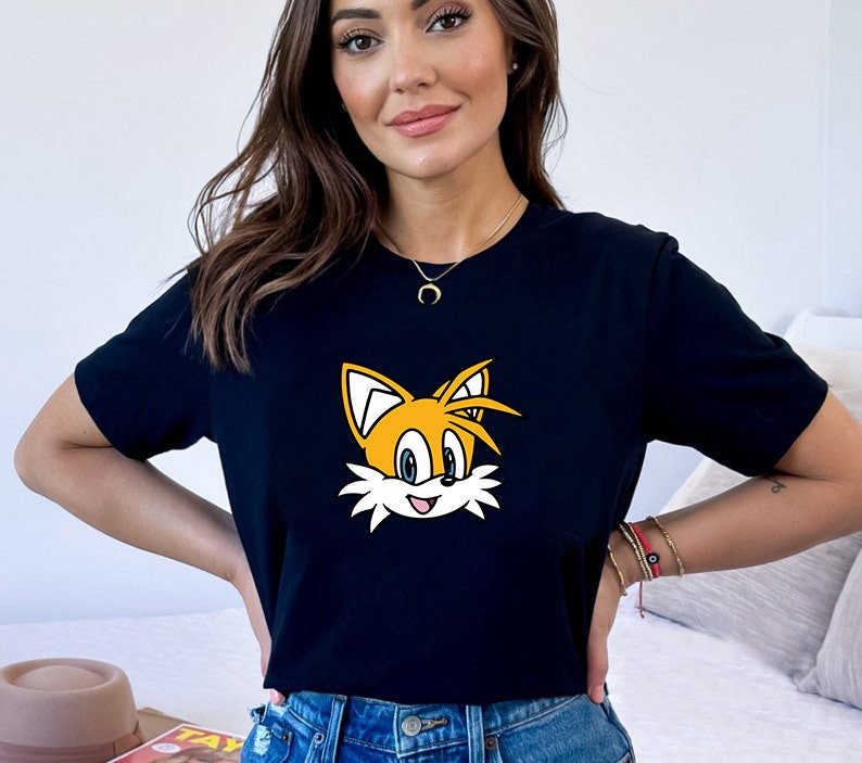 May include: A black t-shirt with a cartoon image of Tails from the Sonic the Hedgehog video game series. The image is yellow, orange, and blue.