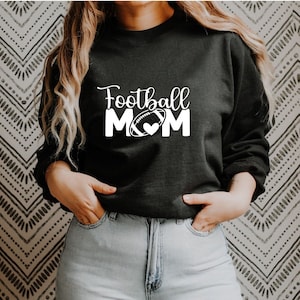 May include: Black sweatshirt with white text that reads "Football Mom" with a football and heart graphic.