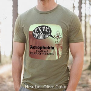May include: A green t-shirt with a cartoon illustration of a person falling off a cliff. The text on the shirt reads "It's not irrational! Acrophobia Irrational Fear of Heights".