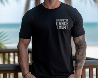 May include: A black t-shirt with the text "DIBS ON THE DANCE MOM" printed on the front in white.