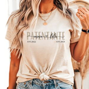 Peut inclure: Un t-shirt beige avec le texte "PATENTANTE emma ♥ felix EST. 2022 EST. 2024" imprimé dessus.
