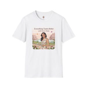 May include: White t-shirt with a graphic of a woman holding a plate of cookies in a garden setting. The text on the graphic reads "Everything Tastes Better with Flower Petals."