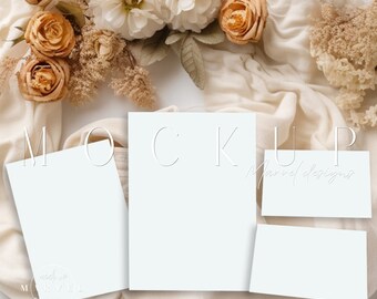 May include: A mockup scene featuring blank white cards of various sizes, arranged on a cream-colored fabric. The cards are surrounded by dried flowers in shades of beige and orange, with the word "MOCKUP" visible.