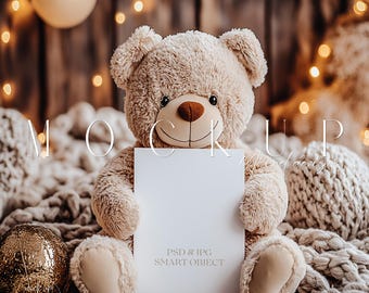 May include: A beige teddy bear holding a blank white card with the text "PSD & JPG SMART OBJECT" in front of a rustic wooden background with string lights. The bear is sitting on a white knitted blanket.