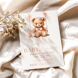 Puede incluir: Una invitaci&oacute;n a una baby shower rosa y marr&oacute;n con una ilustraci&oacute;n de acuarela de un osito de peluche en un columpio. El texto dice "Por favor, &uacute;nase a nosotros para una baby shower en honor a Hailey Smith S&aacute;b 22 Dic. a las cuatro en punto de la tarde 123 Anywhere Street, Anywhere RSVP antes del 16 de noviembre a Sarah al 0412 345 678"