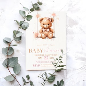 Puede incluir: Una invitaci&oacute;n a una baby shower rosa y dorada con una ilustraci&oacute;n de acuarela de un osito de peluche en un columpio. El texto dice "Por favor, &uacute;nase a nosotros para una baby shower en honor a Hailey Smith, S&aacute;b 22 Dic, a las cuatro en punto de la tarde, 123 Anywhere Street, Anytown. RSVP antes del 16 de noviembre a Sarah al 0412 346."