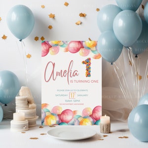 May include: A printable first birthday party invitation with a watercolor design of colorful balloons. The invitation says "Amelia is turning one" and includes the date, time, and location of the party.
