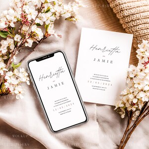 May include: A smartphone and invitation card with the names "Henrietta" and "Jamie" in elegant script. The invitation includes the date 12/05/2024. White flowers and a beige fabric create a soft, romantic setting, ideal for wedding announcements.