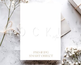May include: A white card mockup with a white background. The card is surrounded by white flowers and a white envelope. The text "PSD & JPG SMART OBJECT" is printed on the card.