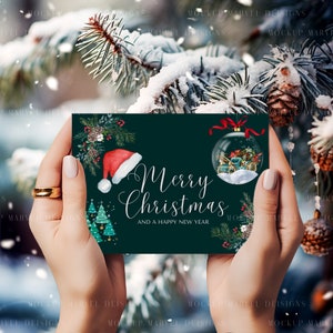 May include: A green Christmas card with a white background and the text "Merry Christmas and a Happy New Year". The card features a red Santa hat, a green pine tree, and a glass ornament with a winter scene.