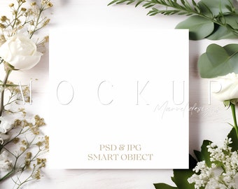 May include: A white card mockup with the text "MOCKUP" and "PSD & JPG SMART OBJECT" on a white wooden background with white and green flowers.