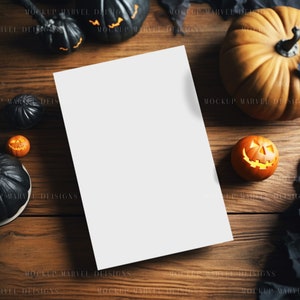 Op de afbeelding: Een wit vel papier ligt op een houten tafel met verschillende pompoenen en pompoenen eromheen. De pompoenen zijn oranje en zwart en sommige hebben gesneden gezichten.