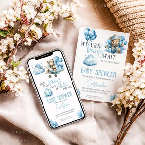 May include: A baby shower invitation and a smartphone screen displaying a similar design. The invitation and phone screen feature a watercolor illustration of a teddy bear in a blue airplane, clouds, and text. The invitation reads "We can bearly wait for the arrival of Baby Spencer."