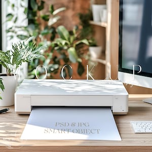 Może przedstawiać: Biała drukarka z arkuszem papieru w podajniku wyjściowym. Papier zawiera napis "PSD & JPG SMART OBJECT". Drukarka stoi na drewnianym stole.