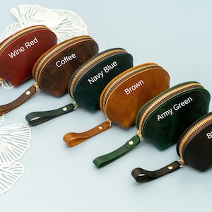 May include: Six small, half-moon shaped leather pouches with zipper closures and a leather strap. The pouches are in the colours wine red, coffee, navy blue, brown, army green, and black. Each pouch has the colour name written on it.