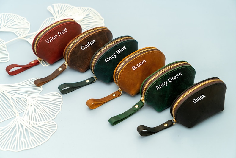 May include: Six small, half-moon shaped leather pouches with zipper closures and a leather strap. The pouches are in the colours wine red, coffee, navy blue, brown, army green, and black. Each pouch has the colour name written on it.