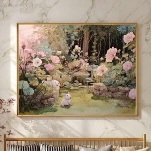 Può includere: Un dipinto incorniciato raffigura una serena scena di giardino con fiori rosa, uno stagno e un coniglio bianco. Il dipinto è appeso sopra una panca dorata con cuscini a righe e fantasia. Un pouf in pelle e piante in vaso completano l'arredamento della stanza.