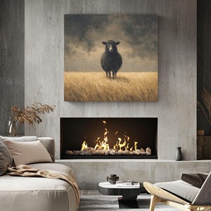K&ouml;nnte beinhalten: Ein gerahmter Leinwanddruck eines schwarzen Schafs, das in einem Feld aus hohem, trockenem Gras unter einem bew&ouml;lkten Himmel steht. Das Kunstwerk h&auml;ngt &uuml;ber einem modernen Kamin mit einem gl&uuml;henden Feuer und dekorativen Steinen. Der Raum ist mit M&ouml;beln in neutralen T&ouml;nen ausgestattet.