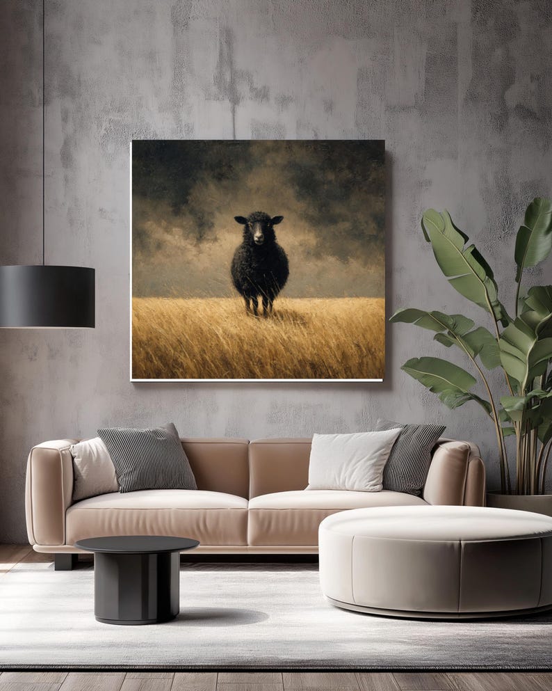 K&ouml;nnte beinhalten: Gerahmter Kunstdruck mit einem schwarzen Schaf, das in einem Feld aus goldenem Gras unter einem bew&ouml;lkten Himmel steht. Das Kunstwerk hat einen rustikalen, malerischen Stil und wird in einem modernen Wohnzimmer pr&auml;sentiert.