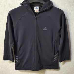 Könnte beinhalten: Dunkelblaue Adidas-Zipfelkapuzenjacke mit Kapuze und langen Ärmeln. Die Jacke hat das Adidas-Logo auf der Brust und drei Streifen am Ärmel. Die Jacke hängt an einem Kleiderbügel.