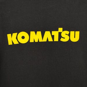May include: Black t-shirt with the word "KOMATSU" printed in yellow block letters. The text is centered and prominently displayed on the front of the shirt. The shirt has a crew neck.