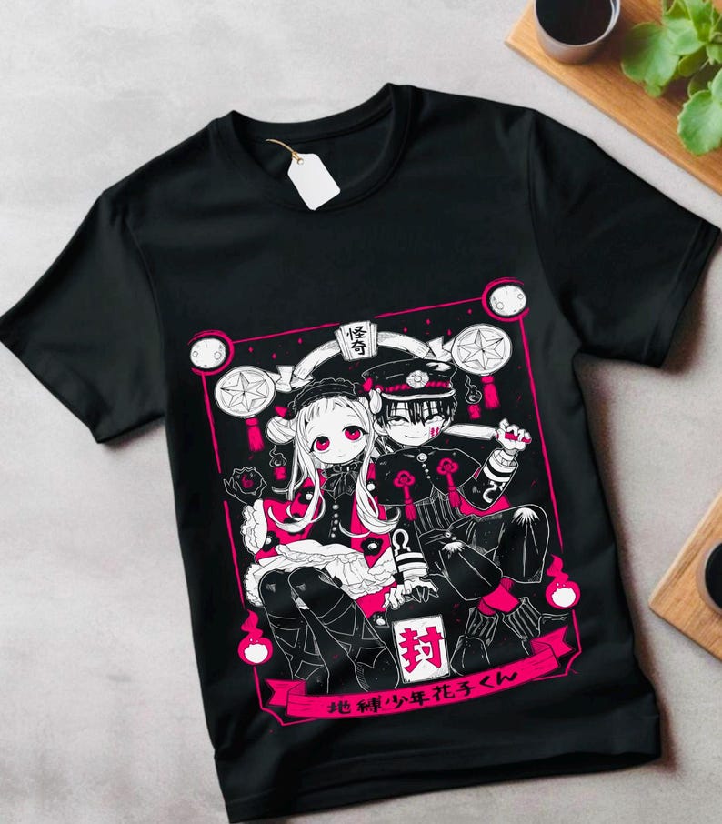 May include: Black t-shirt with a white and pink graphic print of two anime characters. The characters are a girl with long hair and a boy with short hair. The text on the shirt reads "地縛少年花子くん".