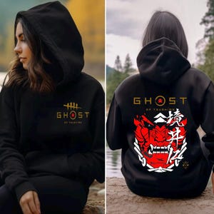May include: Black hooded sweatshirt with a gold "Ghost of Tsushima" logo on the front and a red and white samurai mask with Japanese characters on the back.