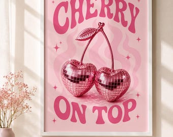 May include: A framed wall art print featuring a light pink background with the text CHERRY ON TOP in bold pink letters. The central graphic depicts two heart-shaped cherries with a reflective, mirrored disco ball texture and a single leaf.