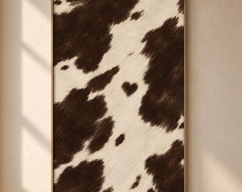 May include: A rectangular wall art piece featuring a brown and white cowhide pattern with a distinct heart-shaped patch in the center. The artwork is enclosed in a thin, metallic frame, displaying a textured, fur-like appearance throughout.