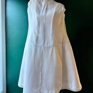 May include: A white satin slip with a gathered skirt and a label that reads "Courreges Paris".