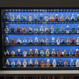 May include: A black display case filled with rows of Lego minifigures. The figures are diverse, with various outfits and accessories. The case has built-in LED lights, illuminating the blue background and the collection of Lego characters.