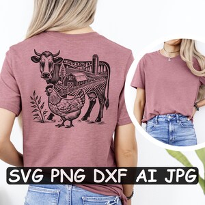 Puede incluir: Una camiseta rosa claro con una ilustraci&oacute;n en blanco y negro de una vaca, un pollo y una granja. El dise&ntilde;o es una silueta de una vaca con un pollo de pie delante de ella. La granja est&aacute; en el fondo.