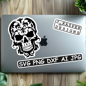 K&ouml;nnte beinhalten: Ein digitaler Download in Schwarzwei&szlig; eines Sch&auml;dels mit aufwendigen floralen Designs. Das Bild enth&auml;lt den Text "SVG PNG DXF AI JPG" und "J. Kasper Designs".