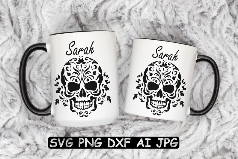 Może przedstawiać: Dwa białe ceramiczne kubki z czarnymi uchwytami i czarnymi obw&oacute;dkami. Każdy kubek ma czarny i biały wz&oacute;r czaszki z kwiatowymi detalami i imieniem "Sarah" nadrukowanym nad czaszką.