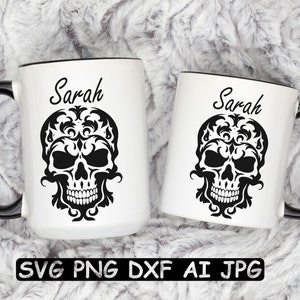 K&ouml;nnte beinhalten: Zwei wei&szlig;e Keramikbecher mit schwarzen Henkeln und schwarzen R&auml;ndern. Die Becher zeigen ein schwarz-wei&szlig;es Bild eines Sch&auml;dels mit floralen Mustern. Der Text "Sarah" ist auf jedem Becher aufgedruckt.