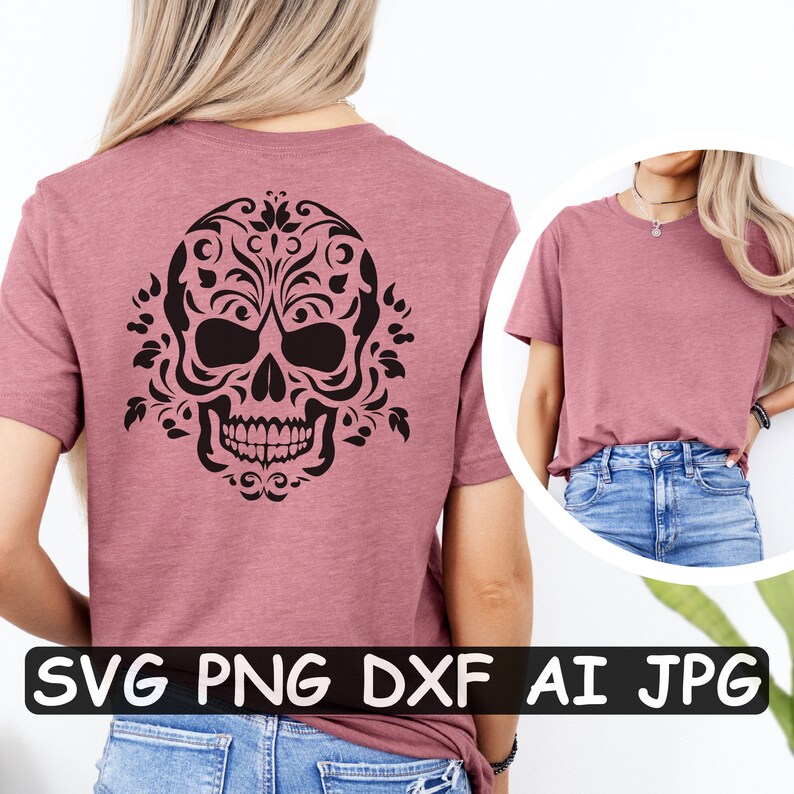 Może przedstawiać: R&oacute;żowy t-shirt z czarnym kwiatowym wzorem czaszki z tyłu. Wz&oacute;r zawiera skomplikowane detale i stylizowaną czaszkę z elementami kwiatowymi. Koszulka jest pokazana na modelce w niebieskich dżinsach.