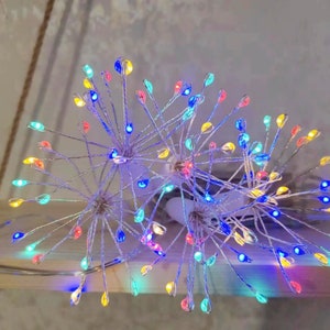 K&ouml;nnte beinhalten: Ein Satz mehrfarbiger Lichterketten in Form eines L&ouml;wenzahns mit silbernem Draht. Die Lichter sind miteinander verbunden und haben einen warmwei&szlig;en Schein.