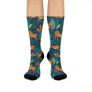 May include: A pair of blue socks with a pattern of orange cheetahs and green leaves.
