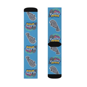 May include: Blue socks with a repeating pattern of gray manatees and the text "FLOATY POTATO". The socks have black cuffs and toes. These socks are designed for comfort and style, perfect for everyday wear.